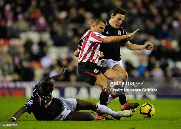 Lee Cattermole of Sunderland is tackled by Dean Whitehead and Mamady Sidibe of Stoke City during the Barclays Premier League match between Sunderland...