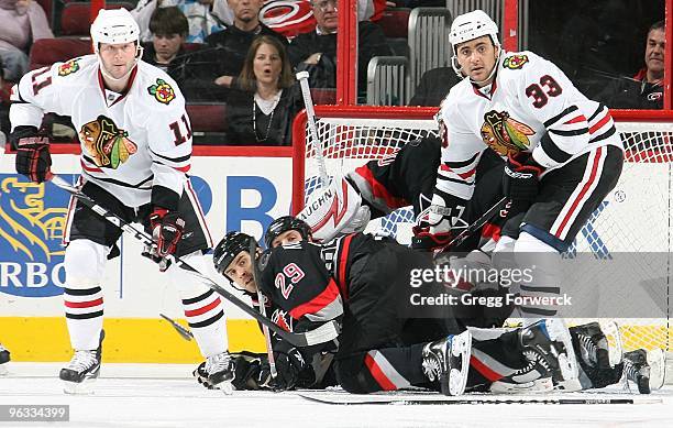 Tom Kostopoulos of the Carolina Hurricanes goes down in the crease attempting to defend the net against Dustin Byfuglien and John Madden of the...