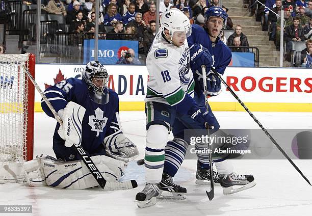 Vesa Toskala and Carl Gunnarsson of the Toronto Maple Leafs battles for the puck with Steve Bernier of the Vancouver Canucks during game action...