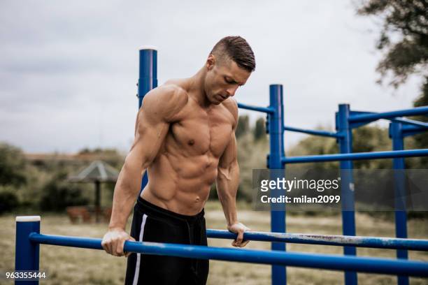 young man doing dips in the local park - biceps stock pictures, royalty-free photos & images