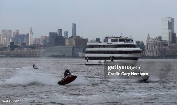 Group of people ride on jet ski's in the Hudson River in front of the skyline of New York City on May 26, 2018 as seen from Jersey City, New Jersey.