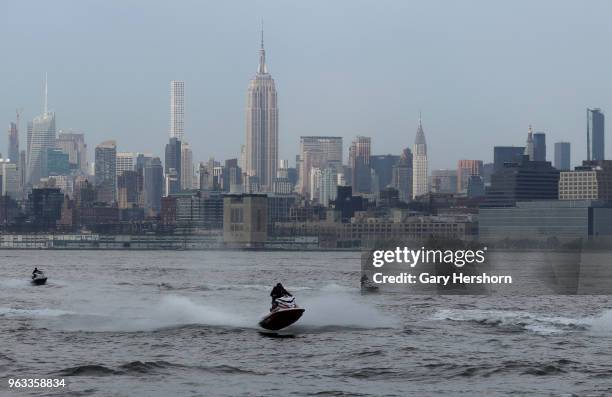 Group of people ride on jet ski's in the Hudson River in front of the Empire State Building in New York City on May 26, 2018 as seen from Jersey...
