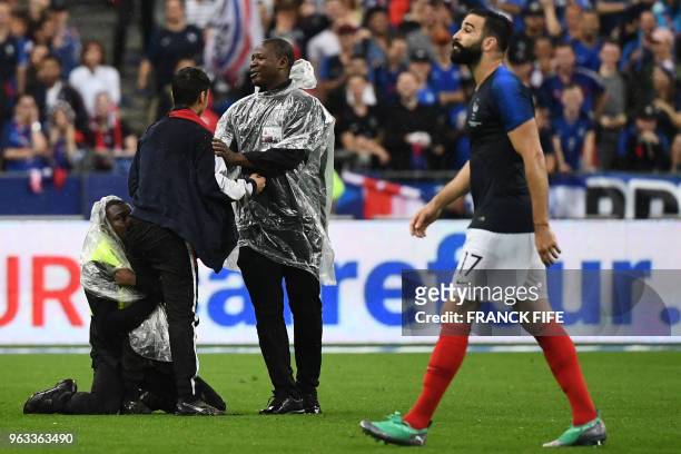Security guard catches a supporter who entered the football pitch during the friendly football match between France and Ireland at the Stade de...