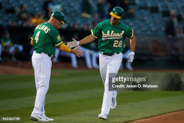 Matt Olson of the Oakland Athletics is congratulated by third base coach Matt Williams after hitting a home run against the Baltimore Orioles during...