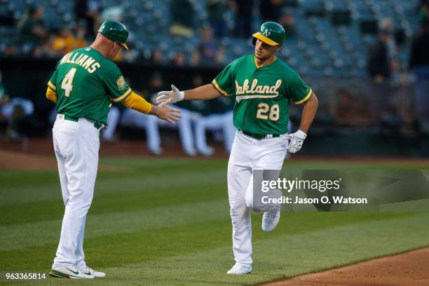 Matt Olson of the Oakland Athletics is congratulated by third base coach Matt Williams after hitting a home run against the Baltimore Orioles during...