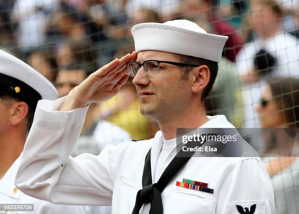 Member of the Navy salutes as the national anthem is played before the game between the New York Yankees and the Houston Astros at Yankee Stadium on...