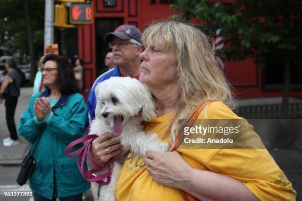 Woman holding her dog stands to watch Memorial Day parade in New York, United States on May 28, 2018.