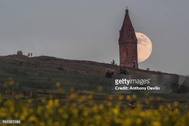 Two walkers approach Hartshead Pike as the Flower Moon rises at 98.6% on May 28, 2018 in Manchester, England. The tower was rebuilt in 1863 by John...