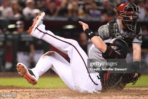 Chris Owings of the Arizona Diamondbacks is safe in front of Tucker Barnhart of the Cincinnati Reds at home plate in the fourth inning of the MLB...