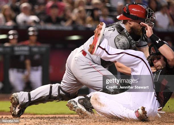 Chris Owings of the Arizona Diamondbacks is safe in front of Tucker Barnhart of the Cincinnati Reds at home plate in the fourth inning of the MLB...