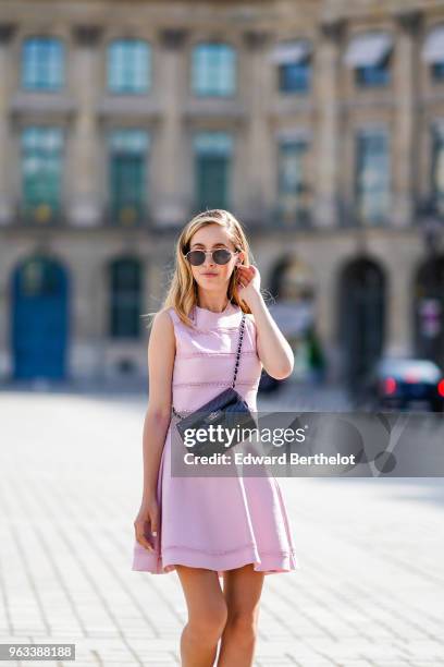 Rosa Crespo, fashion blogger, wears Quay sunglasses, a pink Dior dress with embroidery, a Chanel black leather bag, on May 27, 2018 in Paris, France.