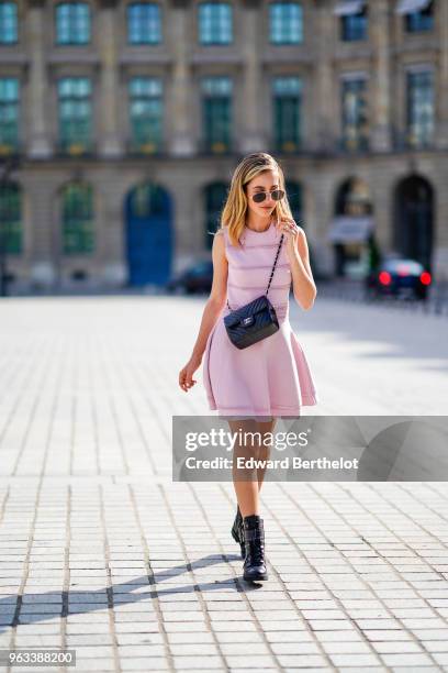 Rosa Crespo, fashion blogger, wears Quay sunglasses, a pink Dior dress with embroidery, a Chanel black leather bag, on May 27, 2018 in Paris, France.