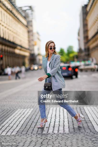 Rosa Crespo, fashion blogger, wears Quay sunglasses, a white t-shirt, blue denim jeans, a Chanel black leather bag, shoes, a green checked gingham...