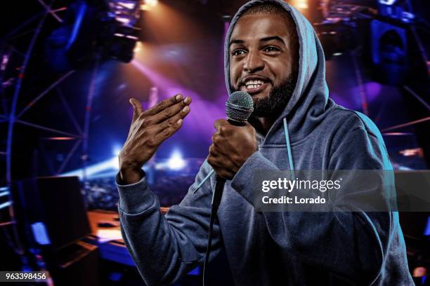 non-caucasian african emcee rapping into a microphone in front of concert lights - emcee imagens e fotografias de stock