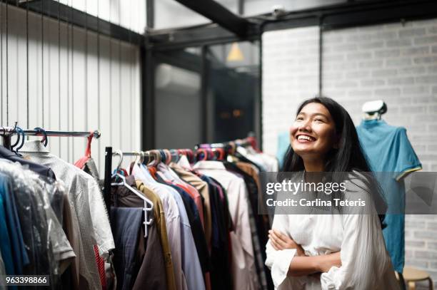 business woman in front of a clothing rack in a boutique - fashion backstage stock pictures, royalty-free photos & images