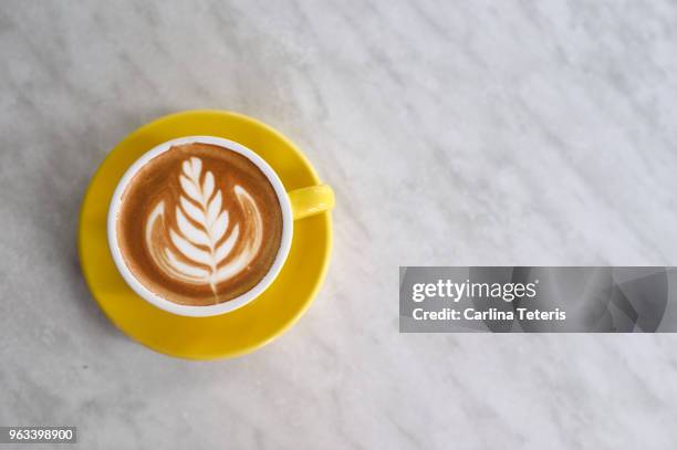 latte art in a yellow cup on a marble table - latte art ストックフォトと画像