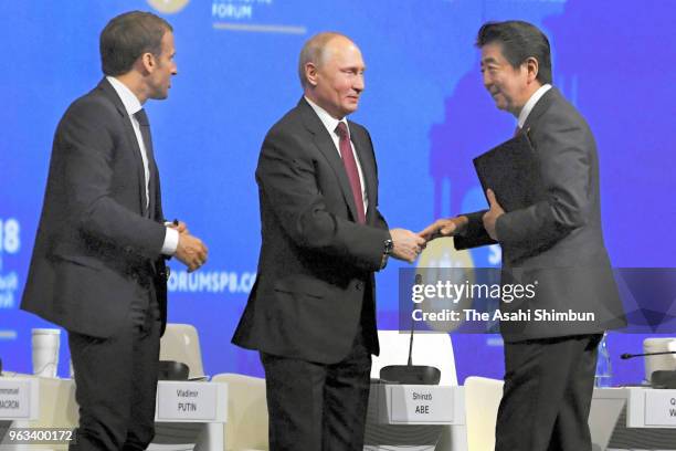 Japanese Prime Minister Shinzo Abe shakes hands with Russian President Vladimir Putin and French President Emmanuel Macron after addresssing during...