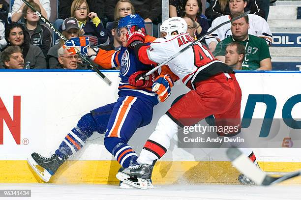 Alex Plante of the Edmonton Oilers is hit along the boards by Andrew Alberts of the Carolina Hurricanes at Rexall Place on February 1, 2010 in...