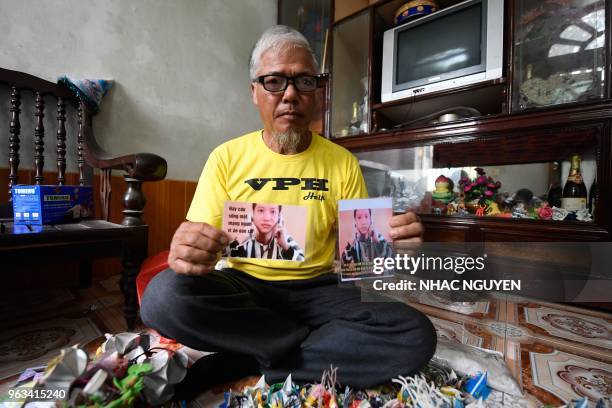 This picture taken on April 24, 2018 shows Nguyen Truong Chinh displaying portraits of his son and death row inmate Nguyen Van Chuong during an...