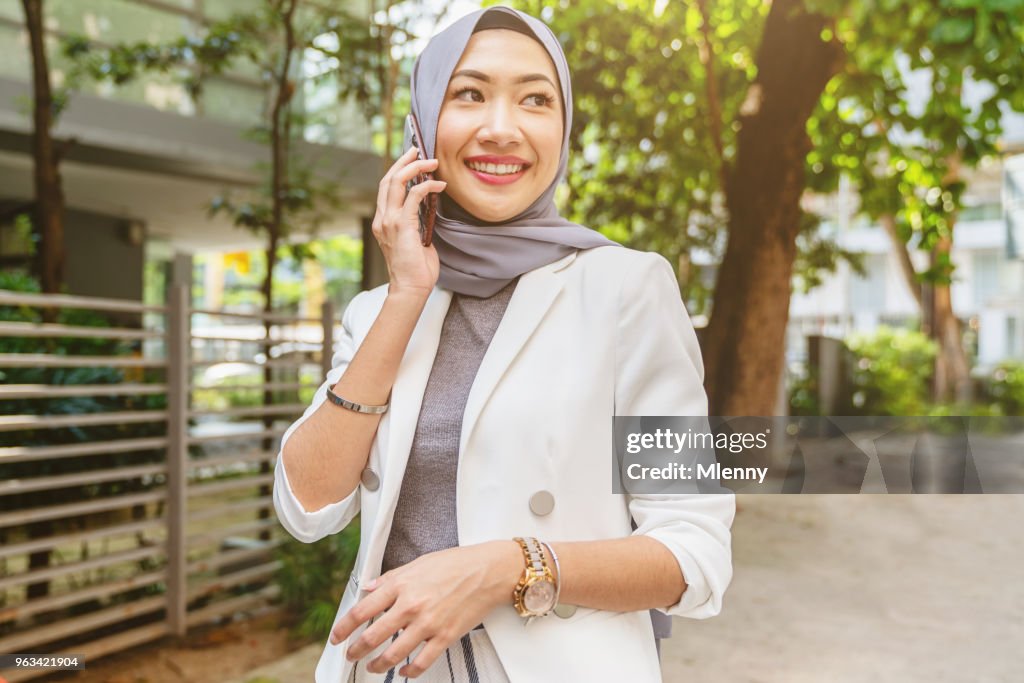 Malaysian woman walking in kuala lumpur talking on mobile phone