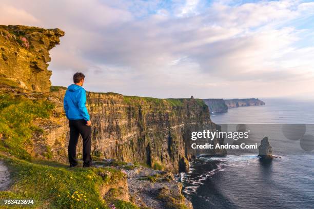 a man standing on the cliffs admires the sunset - cliffs of moher stockfoto's en -beelden