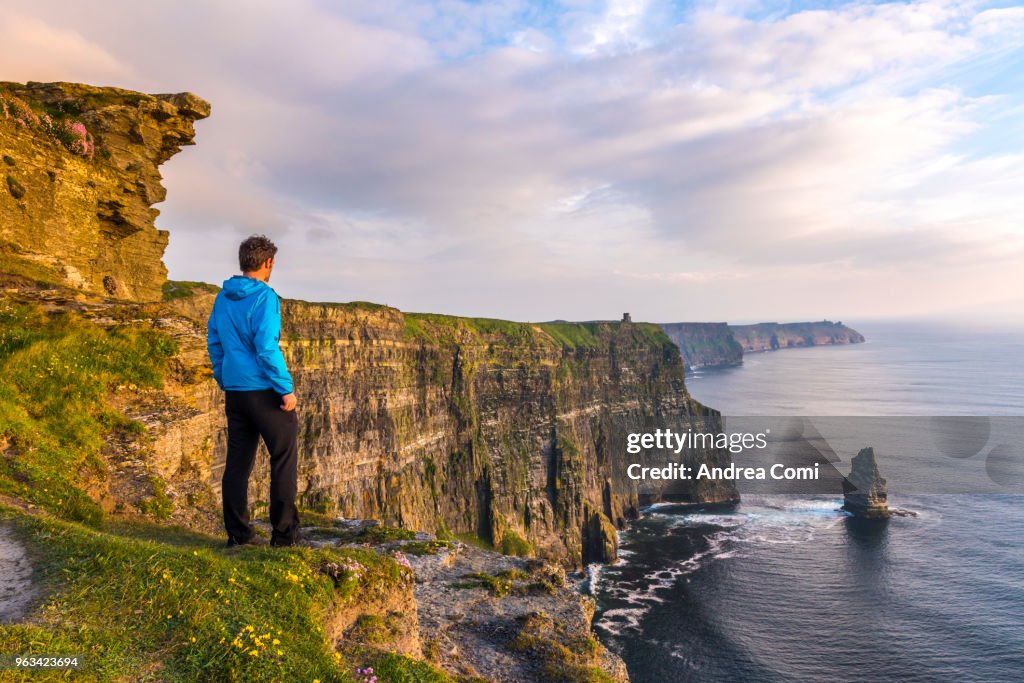 A Man standing on the cliffs admires the sunset