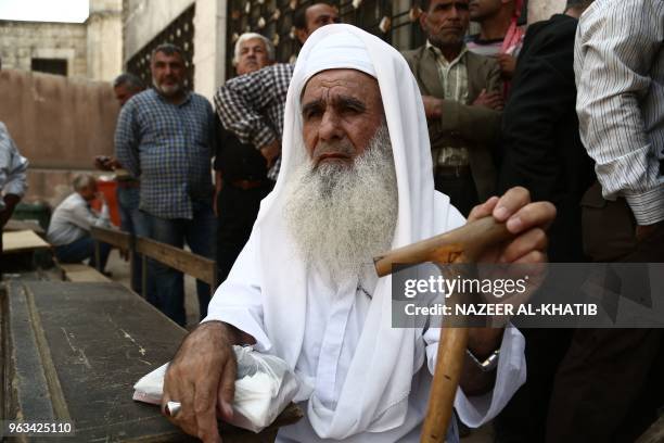 Syrian men displaced from Eastern Ghouta queue to enter the Local Council in Afrin to seek help on May 5, 2018. Displaced from their homes in Syria's...