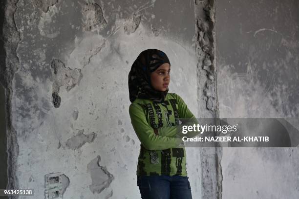 Syrian girl Inas Haymur looks on in Afrin, on May 26, 2018. Displaced from their homes in Syria's Eastern Ghouta, families sought refuge in abandoned...