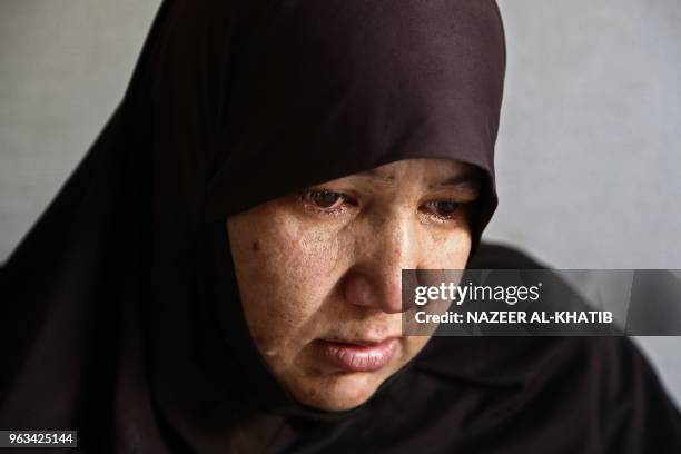 Syrian woman Raifa, wife of Mehdi Haymur, cries as she looks at a picture of her dead son, in Afrin, on May 26, 2018. Displaced from their homes in...