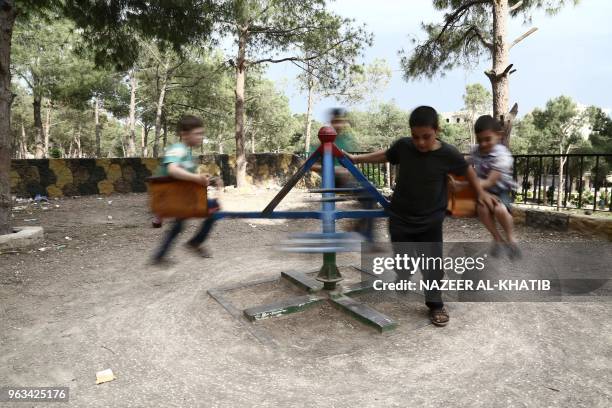 Syrian children displaced from Eastern Ghouta play in a park in Afrin on May 5, 2018. Displaced from their homes in Syria's Eastern Ghouta, families...