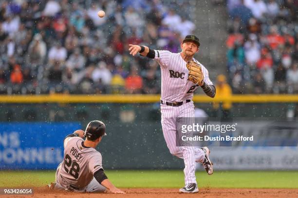 Trevor Story of the Colorado Rockies throws past Buster Posey of the San Francisco Giants to complete a third inning double play during a game\ at...