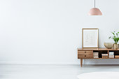 Pink lamp above wooden sideboard