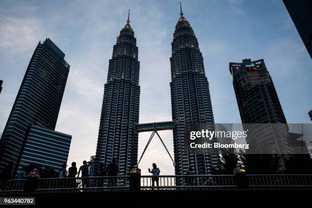 Woman, center, takes a selfie photograph on a bridge in front of the Petronas Twin Towers in Kuala Lumpur, Malaysia, on Friday, May 18, 2018....