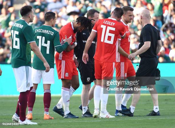 Ashley Williams of Wales is consoled by Javier Hernandez of Mexico as he walks off the pitch following an injury during the first half of their...