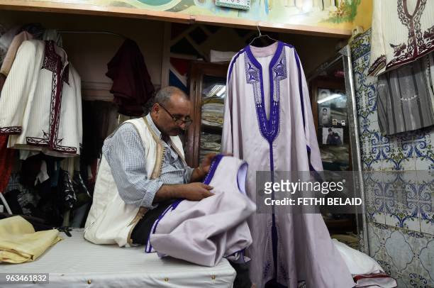 Picture taken on May 21 shows Habib stitching a Jebba at a store in the capital Tunis.