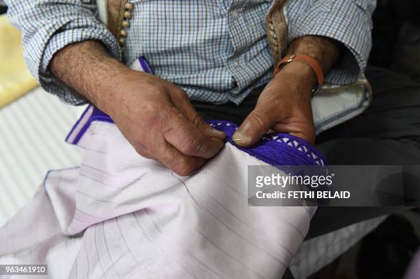 Picture taken on May 21 shows Habib stitching a Jebba at a store in the capital Tunis.