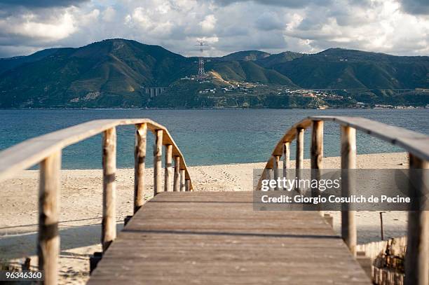 Calabria in the background as seen from a wood bridge in the Sicilian coast in Ganzirri, a small fishing village on the Strait of Messina, in Sicily,...