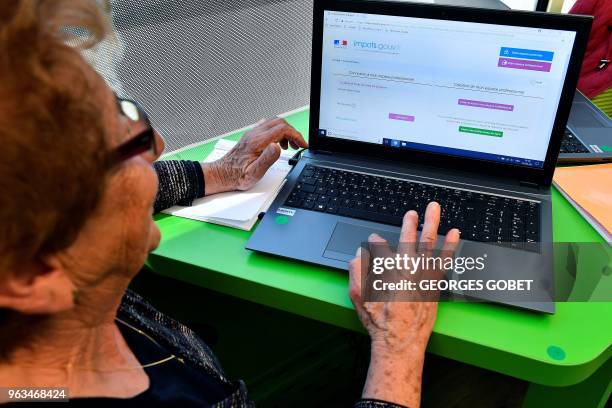 An elderly woman reads on a screen during a computer workshop in the "digital bus in Villandraut, near Sauternes, southwestern France, on May 22,...