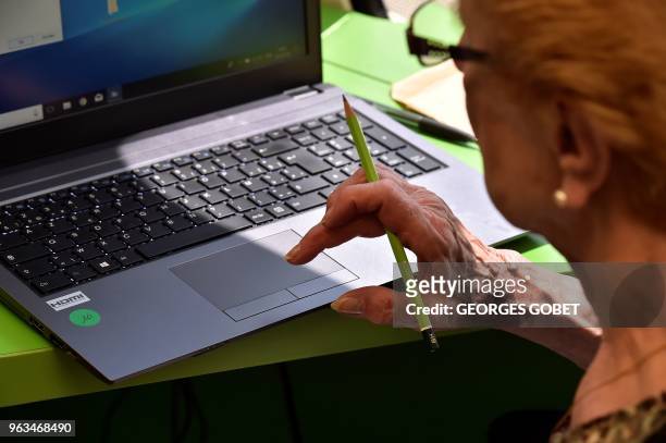 An elderly woman reads on a screen during a computer workshop in the "digital bus in Villandraut, near Sauternes, southwestern France, on May 22,...