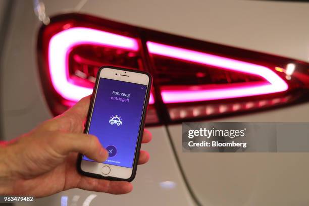 An employee uses a smartphone with the Chark.me app to unlock a Mercedes-Benz A200 automobile, manufactured by Daimler AG, during a demonstration for...