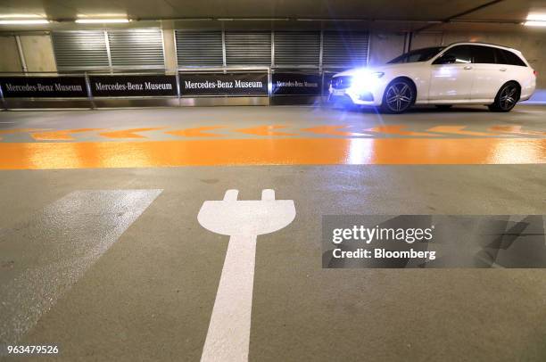 An electric automobile charging symbol sits in a parking space during an automated parking demonstration at the Mercedes-Benz TecDay event in...