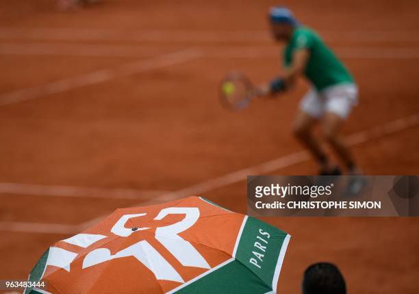 Spectators shelter under umbrellas as rain falls during the men's singles first round match between Croatia's Marin Cilic and Australia's James...
