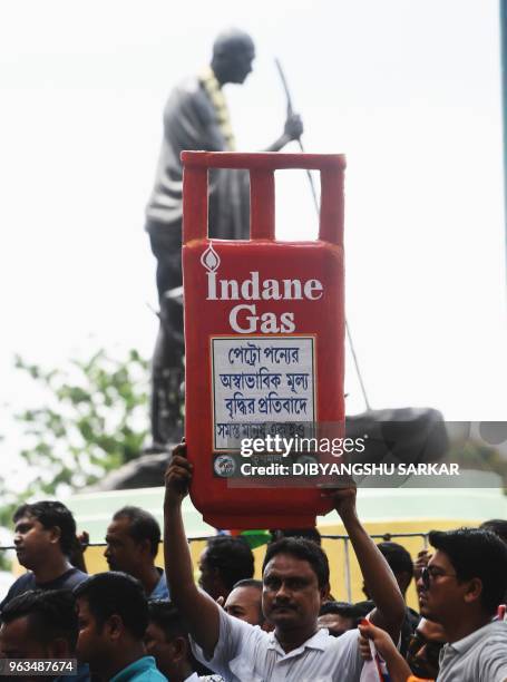 An activist of Trinamool Congress party holds a cut-out replica of LPG cylinder during a protest against the Bharatiya Janata Party lead central...