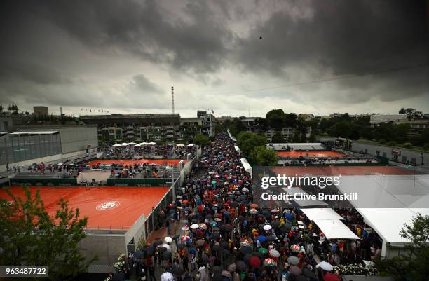 Spectators make their way out of the ground during a rain delay on day three of the 2018 French Open at Roland Garros on May 29, 2018 in Paris,...