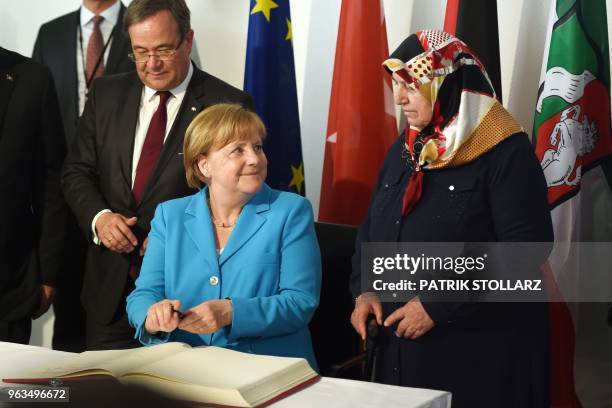 German Chancellor Angela Merkel looks to Mevlude Genc , mother, grandmother and aunt of the victims as she signs the guestbook beside North...