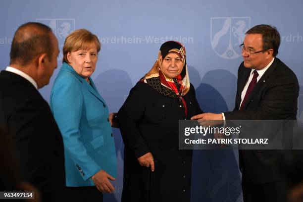 German Chancellor Angela Merkel reacts as she prepares to pose for a picture beside Mevlude Genc , mother, grandmother and aunt of the victims, North...