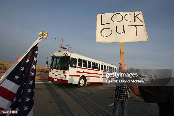 Locked out workers hold signs as buses carry replacement workers from the Rio Tinto Borax mine at the end of their shifts two days after mine owners...