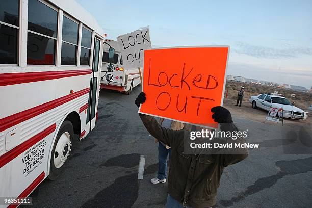 Locked out workers hold signs as buses bring replacement workers to the Rio Tinto Borax mine during shift change two days after mine owners locked...