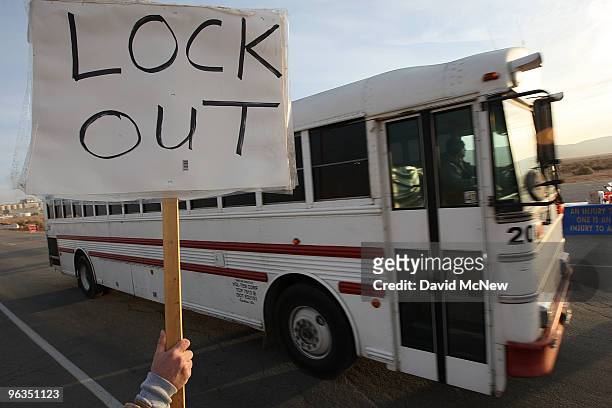 Locked out workers hold signs as buses carry replacement workers from the Rio Tinto Borax mine at the end of their shifts two days after mine owners...