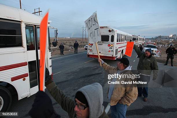 Locked out workers hold signs as buses bring replacement workers to the Rio Tinto Borax mine during shift change two days after mine owners locked...